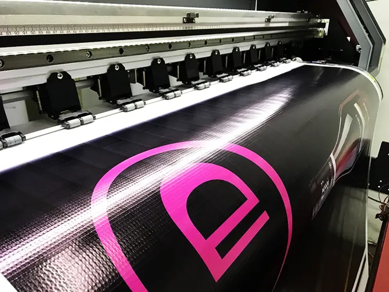 Lona publicitaria impresa en gran formato saliendo de la impresora